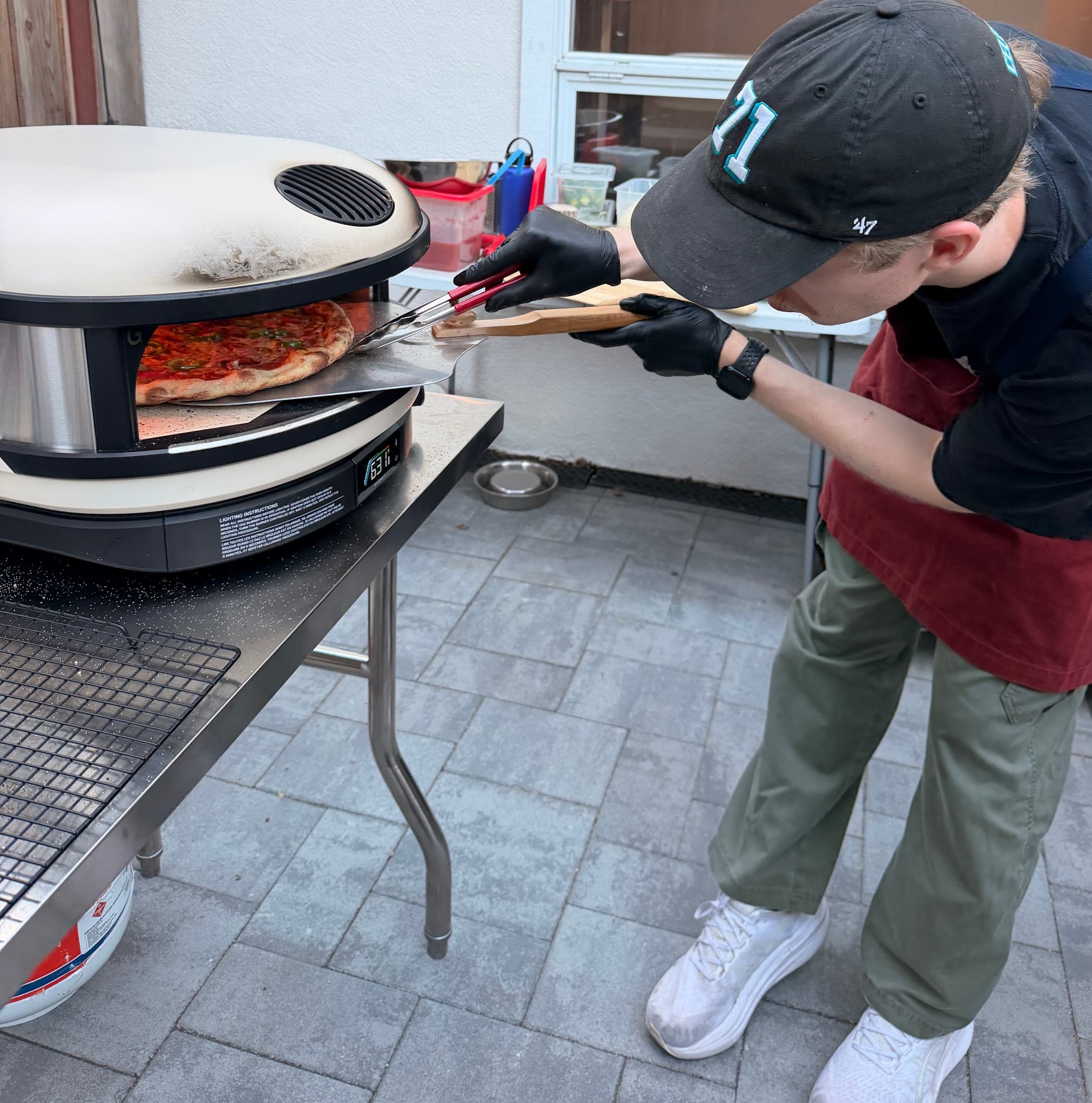 Scuf turning a pepperoni pie inside the live-fire oven.